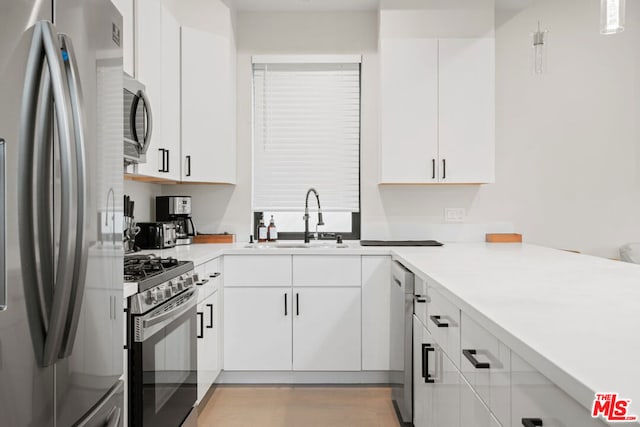 kitchen with pendant lighting, sink, white cabinetry, and appliances with stainless steel finishes