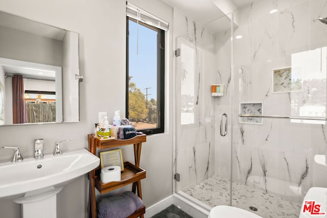 bathroom featuring sink, toilet, and a shower with door