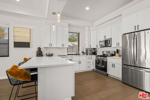 kitchen featuring kitchen peninsula, appliances with stainless steel finishes, decorative light fixtures, a kitchen breakfast bar, and white cabinets