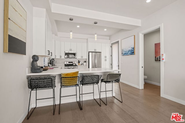 kitchen featuring white cabinetry, kitchen peninsula, appliances with stainless steel finishes, a breakfast bar, and sink