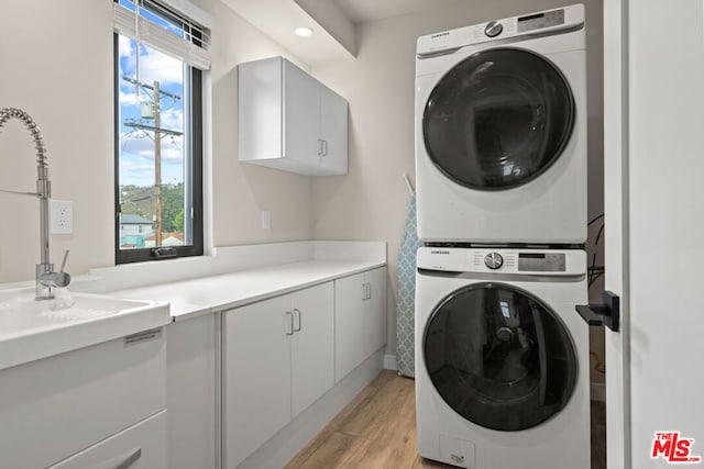 washroom with cabinets, stacked washer / dryer, and light hardwood / wood-style flooring