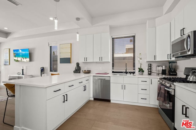 kitchen featuring decorative light fixtures, kitchen peninsula, stainless steel appliances, and white cabinetry