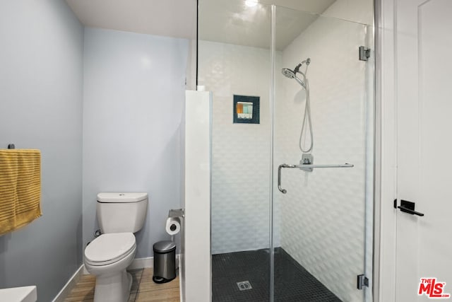 bathroom with toilet, wood-type flooring, and an enclosed shower