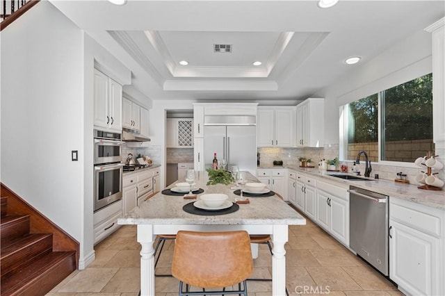 kitchen featuring a breakfast bar, stainless steel appliances, a raised ceiling, and a kitchen island