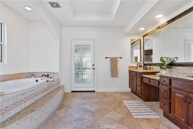 bathroom with tiled bath, ornamental molding, a raised ceiling, and vanity