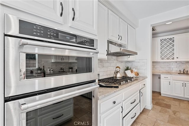 kitchen featuring decorative backsplash, light stone counters, white cabinetry, and stainless steel appliances