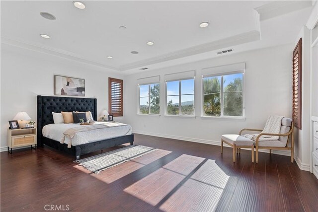 bedroom with dark hardwood / wood-style floors, ornamental molding, and a raised ceiling