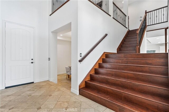 foyer entrance with light tile patterned floors and a towering ceiling