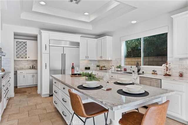 kitchen featuring a raised ceiling, a breakfast bar, sink, and tasteful backsplash