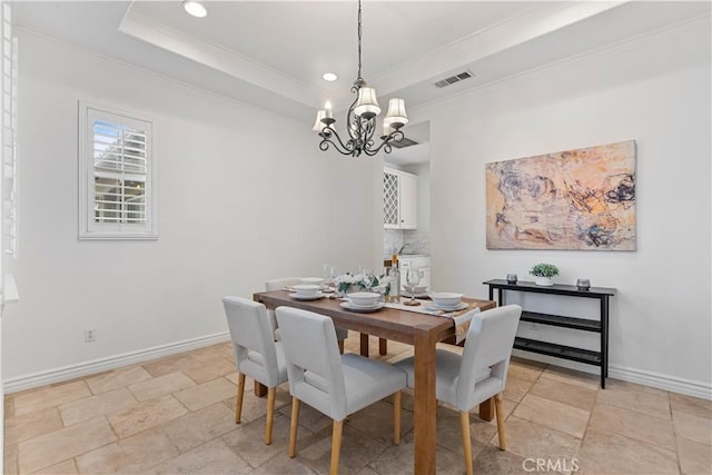 dining area featuring crown molding, a raised ceiling, and a notable chandelier