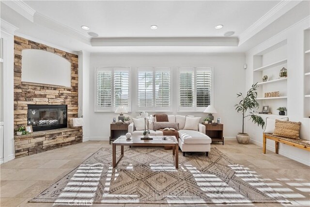 sitting room featuring a fireplace, built in shelves, a tray ceiling, and a healthy amount of sunlight