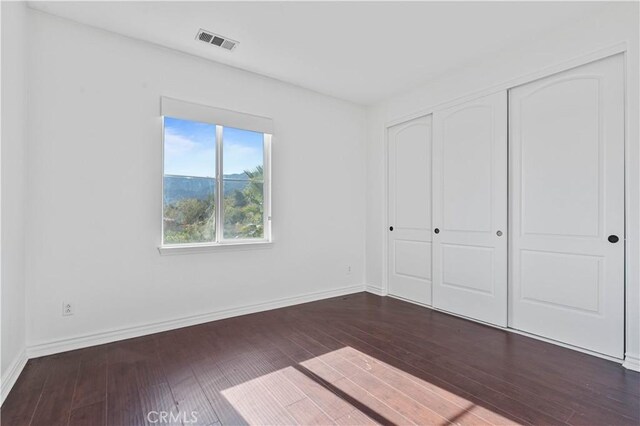 unfurnished bedroom with a closet and dark hardwood / wood-style flooring