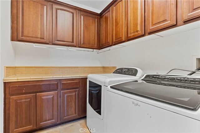 laundry room featuring cabinets, washer and clothes dryer, and light tile patterned flooring