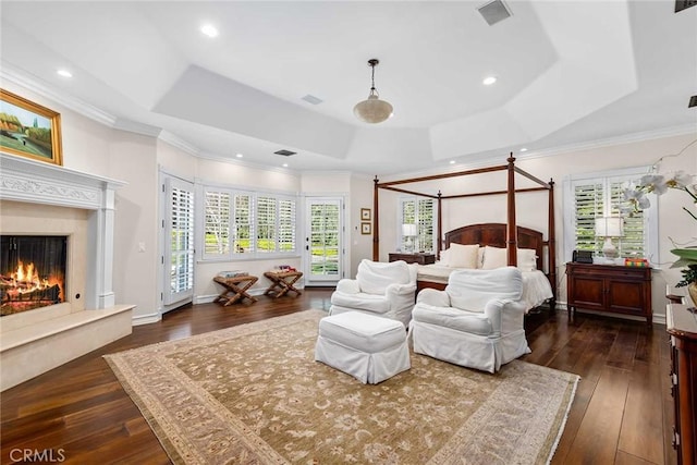 bedroom featuring access to exterior, dark hardwood / wood-style floors, crown molding, a tray ceiling, and a high end fireplace