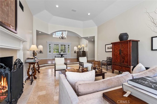 living room featuring an inviting chandelier, french doors, a fireplace, and a tray ceiling