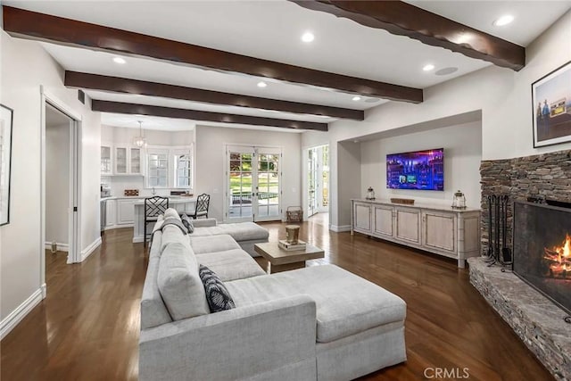 living room featuring beam ceiling, french doors, dark hardwood / wood-style floors, and a stone fireplace