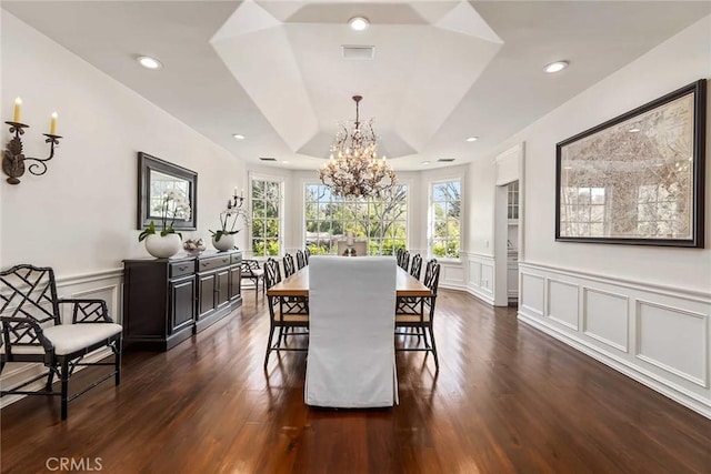 dining area featuring a raised ceiling, dark hardwood / wood-style floors, and an inviting chandelier