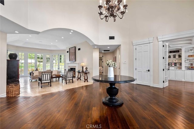 foyer featuring a chandelier, a raised ceiling, a towering ceiling, and hardwood / wood-style flooring