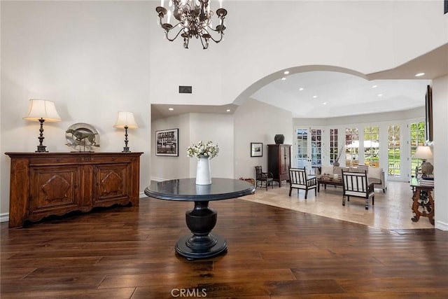 foyer entrance with french doors, dark hardwood / wood-style floors, and a notable chandelier