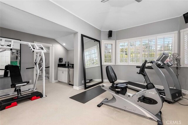 exercise area featuring light carpet and vaulted ceiling