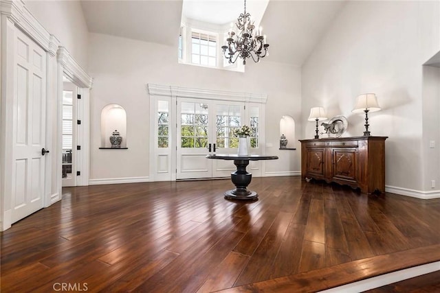 entrance foyer featuring an inviting chandelier, dark hardwood / wood-style flooring, french doors, and high vaulted ceiling