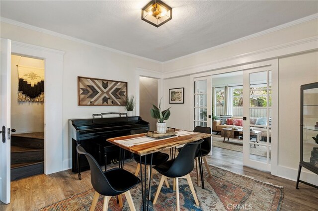 dining room with french doors, crown molding, and wood-type flooring