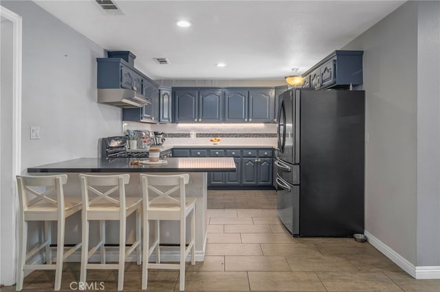 kitchen with blue cabinetry, stainless steel fridge, kitchen peninsula, and stove