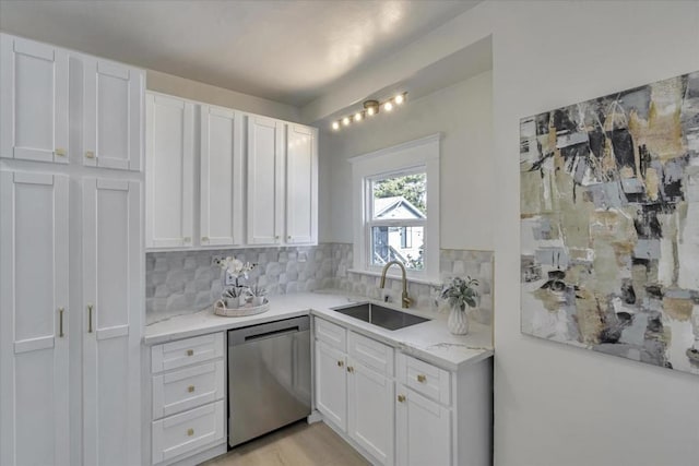 kitchen with tasteful backsplash, dishwasher, sink, light stone countertops, and white cabinets