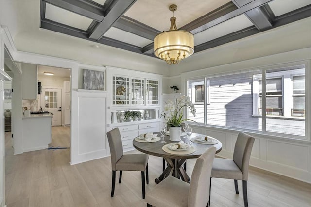 dining room with a chandelier, beam ceiling, light hardwood / wood-style floors, and coffered ceiling