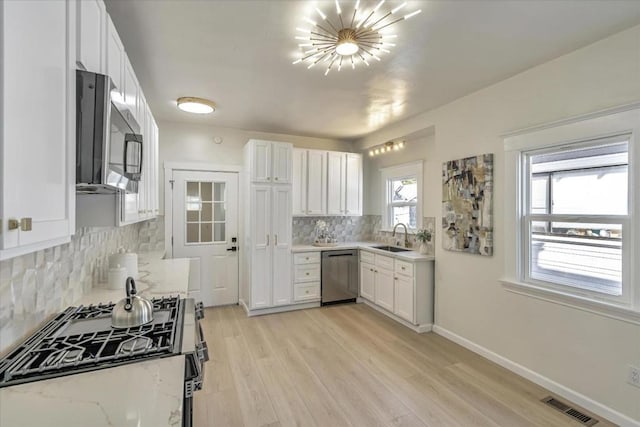 kitchen featuring light stone countertops, appliances with stainless steel finishes, white cabinetry, sink, and backsplash