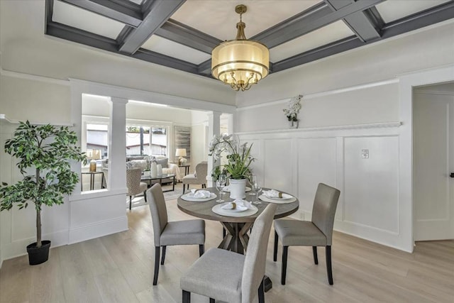 dining room featuring ornate columns, light hardwood / wood-style floors, a chandelier, beam ceiling, and coffered ceiling