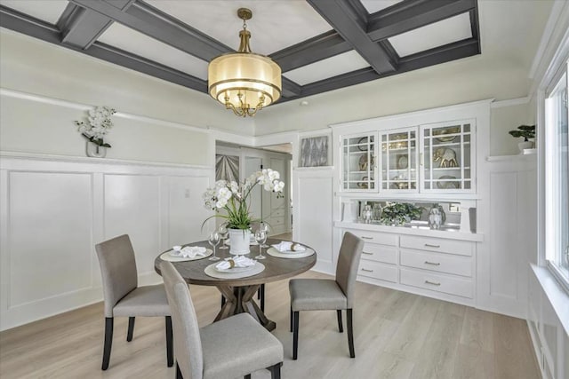 dining space featuring beamed ceiling, an inviting chandelier, coffered ceiling, and light hardwood / wood-style flooring