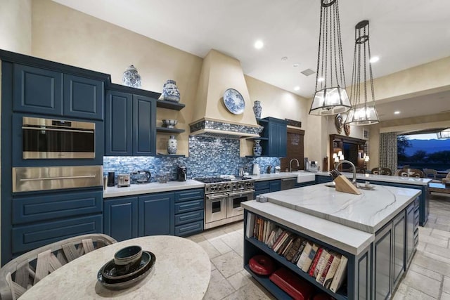 kitchen featuring backsplash, a kitchen island with sink, stainless steel appliances, custom range hood, and blue cabinets