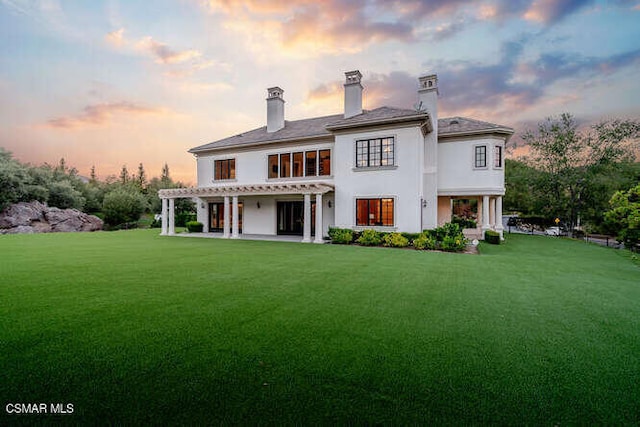 back house at dusk featuring a yard