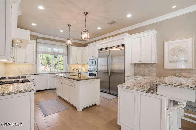 kitchen featuring hanging light fixtures, backsplash, built in appliances, and white cabinetry