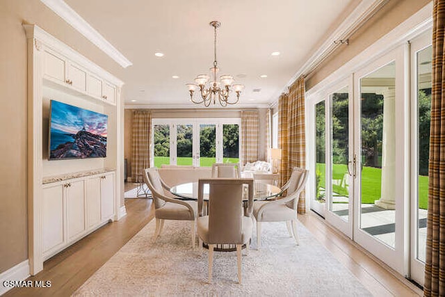 dining space featuring an inviting chandelier, crown molding, light hardwood / wood-style flooring, and french doors