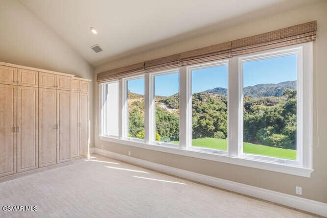 unfurnished bedroom featuring a closet, lofted ceiling, a mountain view, and multiple windows