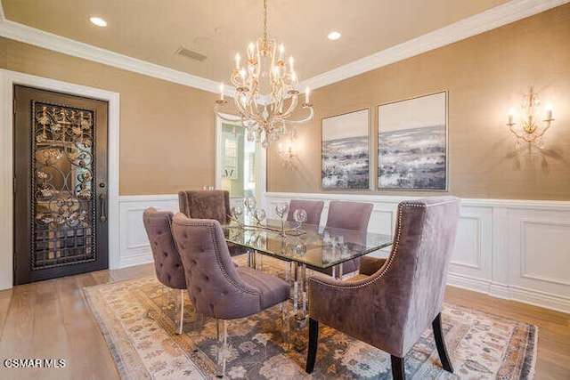 dining area with a notable chandelier, ornamental molding, and light hardwood / wood-style floors