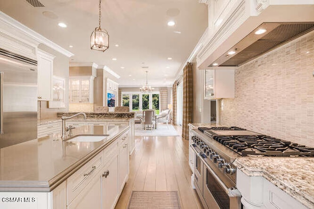 kitchen with white cabinetry, sink, hanging light fixtures, and custom range hood