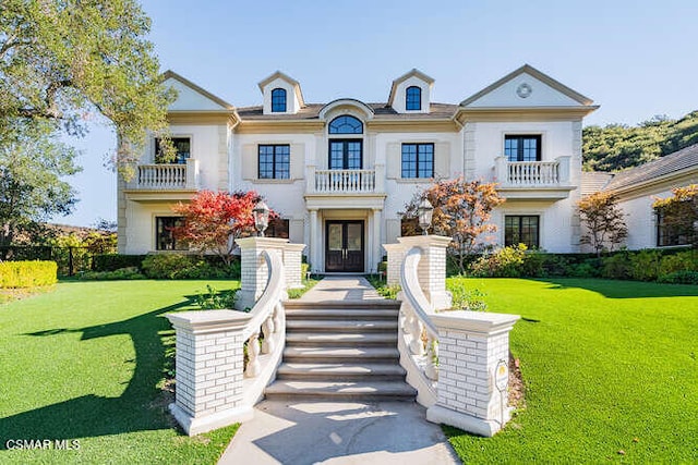 french country style house featuring a balcony and a front yard