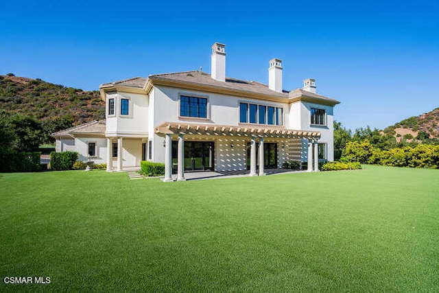 rear view of property featuring a pergola, a yard, and a patio