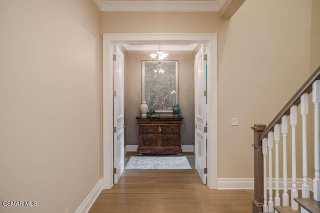 hall featuring wood-type flooring, a notable chandelier, and ornamental molding