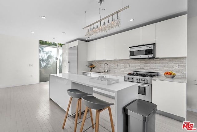 kitchen featuring decorative backsplash, sink, white cabinetry, stainless steel appliances, and a wall of windows