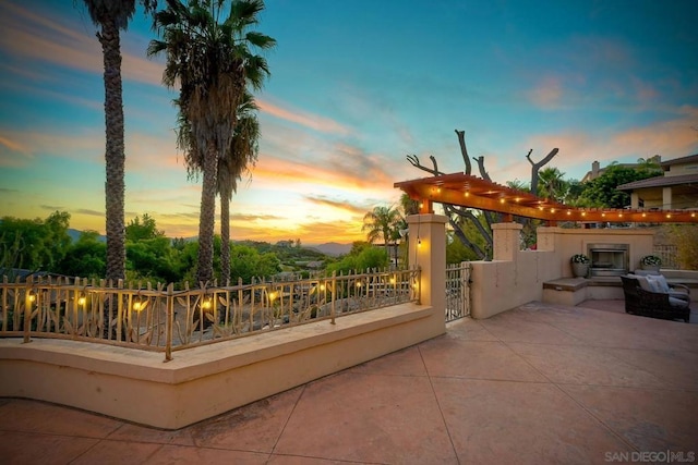 patio terrace at dusk featuring a tiled fireplace