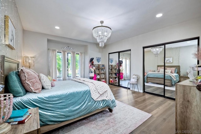 bedroom with multiple closets, a chandelier, and hardwood / wood-style floors