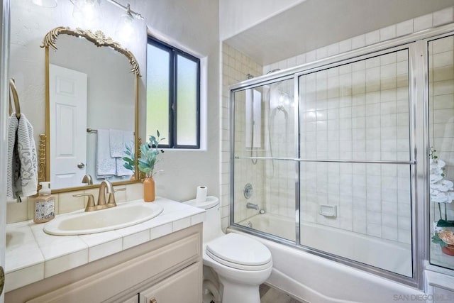 full bathroom with toilet, vanity, and shower / bath combination with glass door