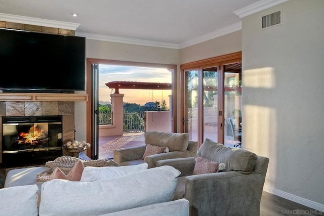 living room featuring wood-type flooring, a tile fireplace, and crown molding