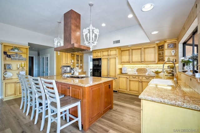 kitchen featuring island range hood, sink, a chandelier, pendant lighting, and black appliances