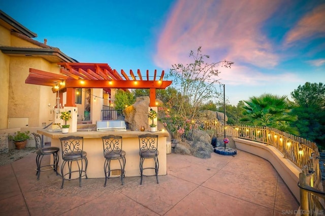 patio terrace at dusk featuring a pergola and an outdoor bar