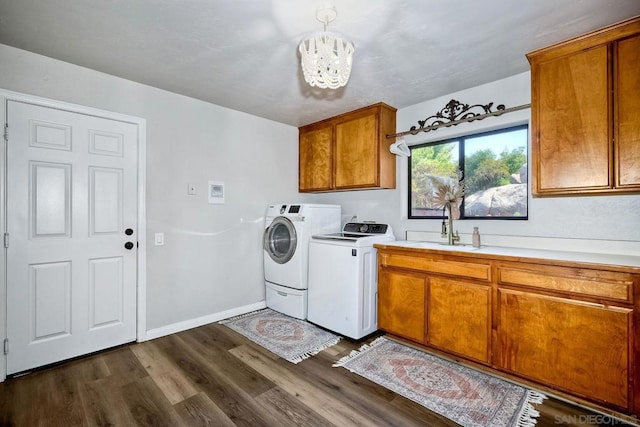 laundry room featuring washing machine and clothes dryer, dark wood-type flooring, cabinets, a chandelier, and sink